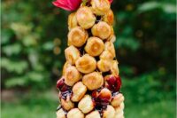 a small and delicious croquembouche topped with fresh berry jam and pink blooms is a great idea for a summer wedding