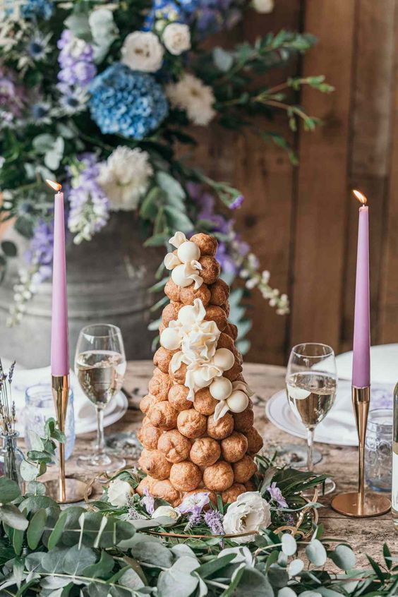 a small and lovely croquembouche with white blooms and white chocolate spheres decorated with greenery and blooms