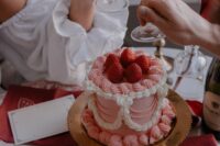 a small and lovely pink lambeth wedding cake with sugar patterns and strawberries on top is a romantic idea