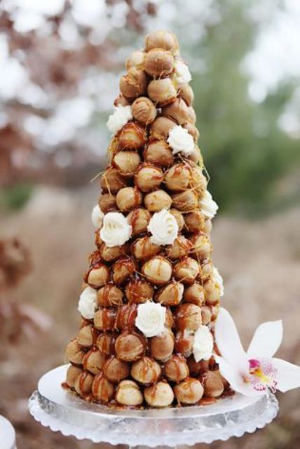a small croquembouche decorated with caramel drip, white blooms is a stylish idea for a modern and exquisite wedding
