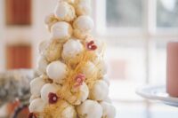 a small iced croquembocueh with caramel icing and little pink blooms is a lovely idea for a modern wedding