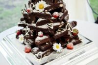 a stack of brownies decorated with chamomiles, fresh strawberries and hearts is a cool rustic wedding idea that loosk super cute