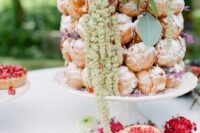 a super creative and bright croquembouche with sugar icing, bold blooms of various kinds and greenery for a boho wedding