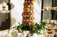 a tall croqumebouche with sugar icing and yellow blooms plus greenery around is an elegant and chic idea for a wedding
