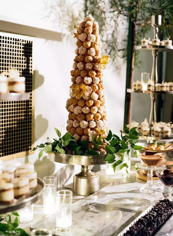 a tall croqumebouche with sugar icing and yellow blooms plus greenery around is an elegant and chic idea for a wedding