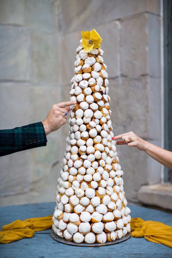 a tall iced croquembouche topped with a yellow bloom is a gorgeous idea for a sophisticated wedding