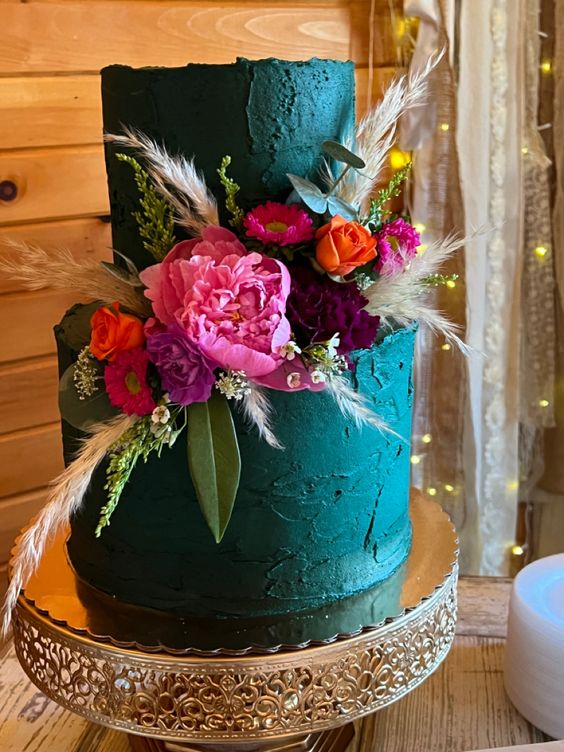 a teal textural wedding cake with a rough edge, bright red, pink, orange and burgundy blooms, greenery and grasses is a gorgeous idea for a fall wedding