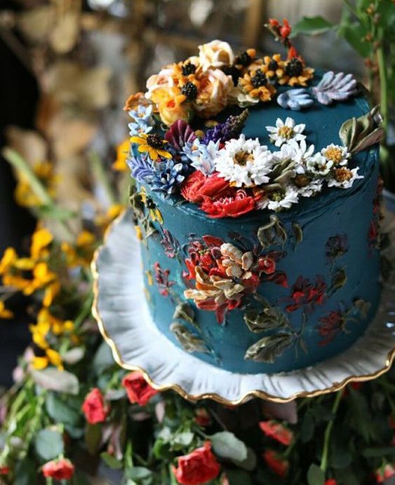 a teal textural wedding cake with lots of colorful sugar blooms and some natural ones for a garden wedding
