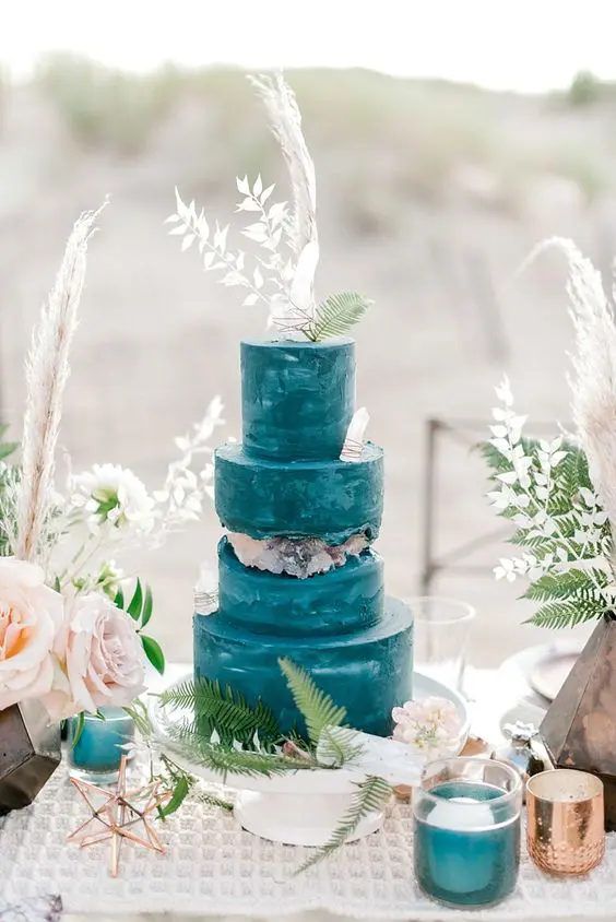 a teal watercolor wedding cake with neutral geodes and white grasses and leaves on top is a catchy boho wedding idea