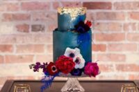 a teal wedding cake with a textural edge and gold leaf on top, with bold blooms and foliage is a lovely idea for a fall wedding
