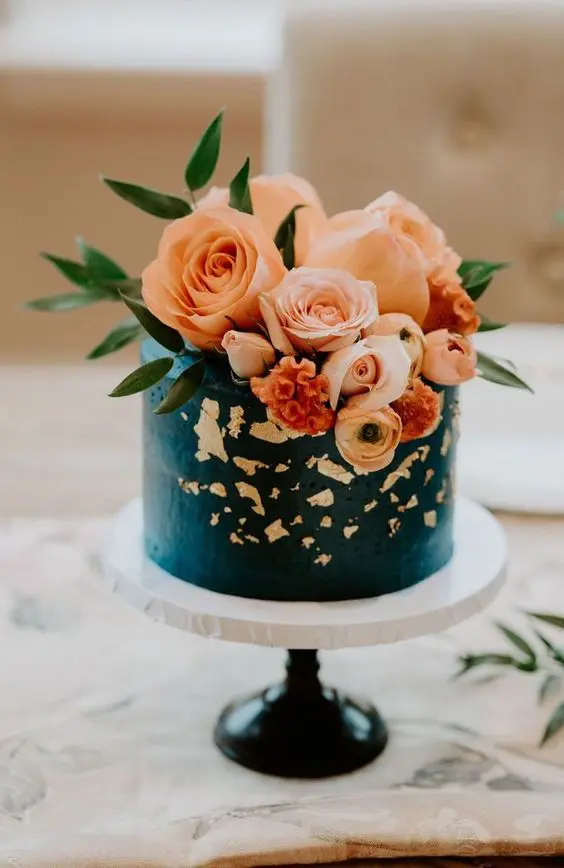 a teal wedding cake with a texture, with gold leaf and peachy and rust blooms and greenery is a stylish solution for a wedding in this color scheme