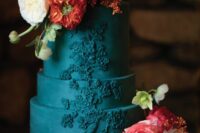 a teal wedding cake with a whimsical pattern, with white, coral and orange blooms and greenery for a wedding with much color