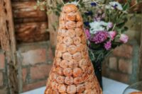 a traditional croquembouche decorated with caramel, caramel icing and funfett and with a gold calligraphy topper is wow