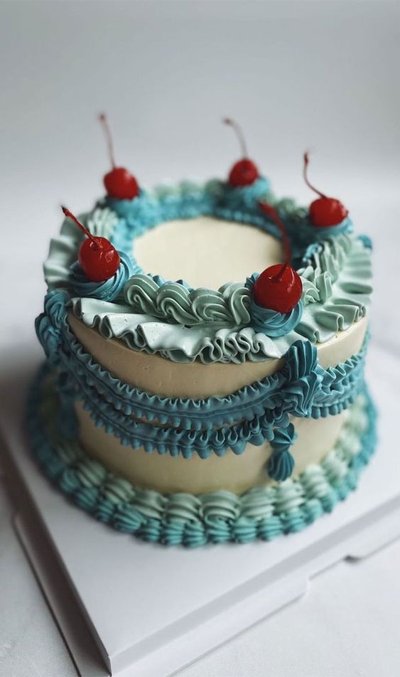 a white, mint and turquoise lambeth wedding cake topped with cherries is an adorable idea for a spring or summer wedding