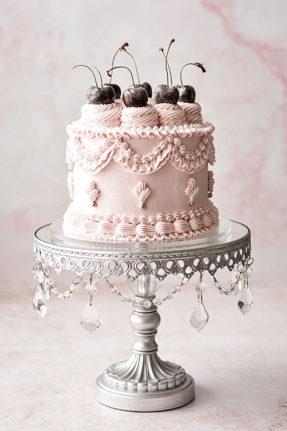 an elegant blush lambeth wedding cake with sugar patterns, gold beads and dark gilded cherries on top for a chic wedding