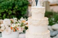 an elegant neutral lambeth wedding cake with sugar detailing and a bold couple cake topper plus a banner