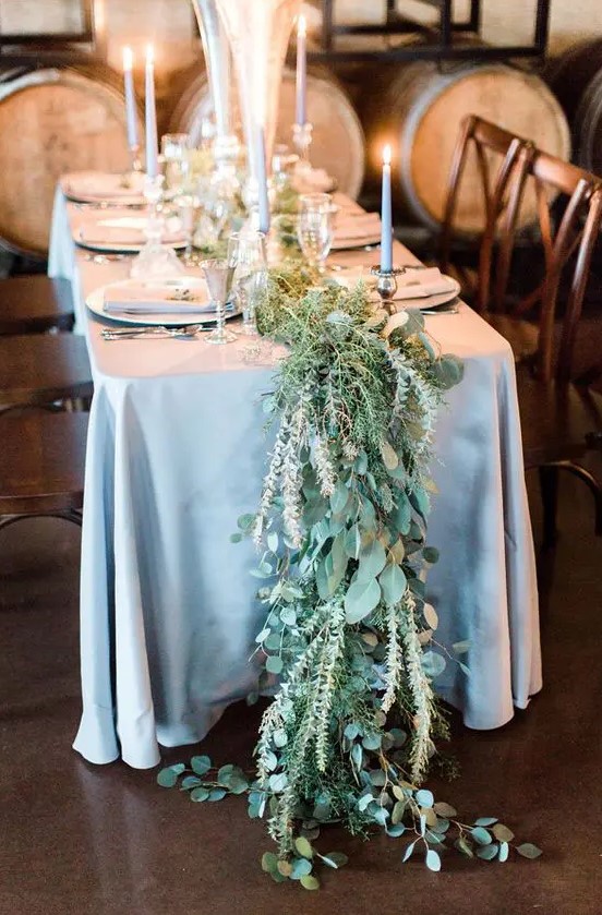 a greenery and foliage table runner in pale shades looks organic with a dusty blue tablecloth