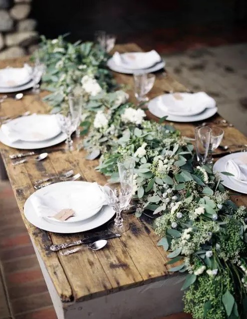 a lush and textural greenery table runner with berries is a chic idea for a winter tablescape