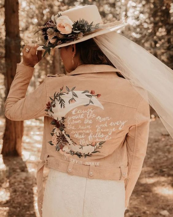 a pink leather jacket with a painted half moon, blooms and greenery and a quote is a lovely idea for a romantic bride