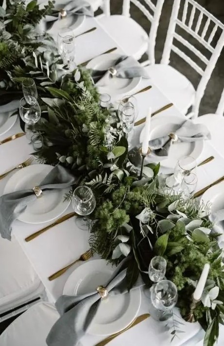 a lush woodland-inspired greenery table garland with various kinds of eucalyptus, moss and ferns
