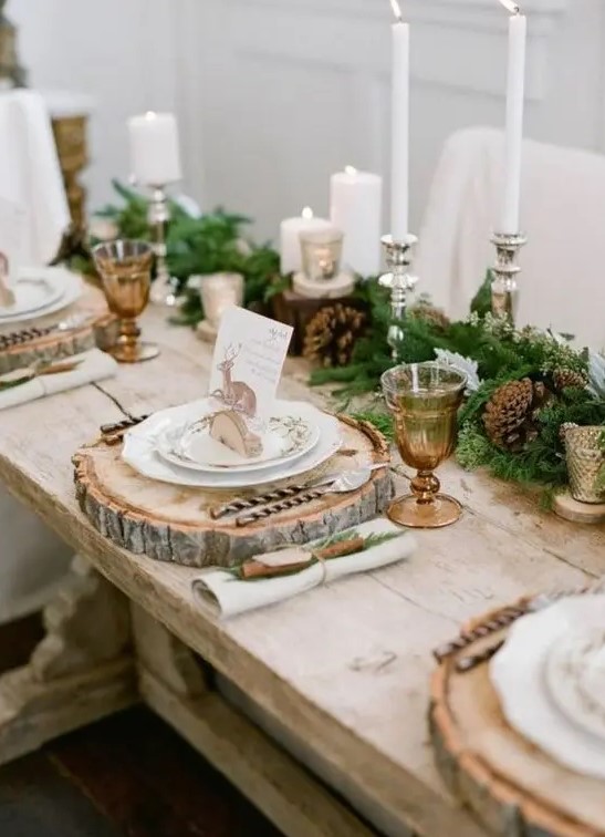 rustic Christmas wedding tablescape with an evergreen and pinecone runner, various candles and wood slice placemats