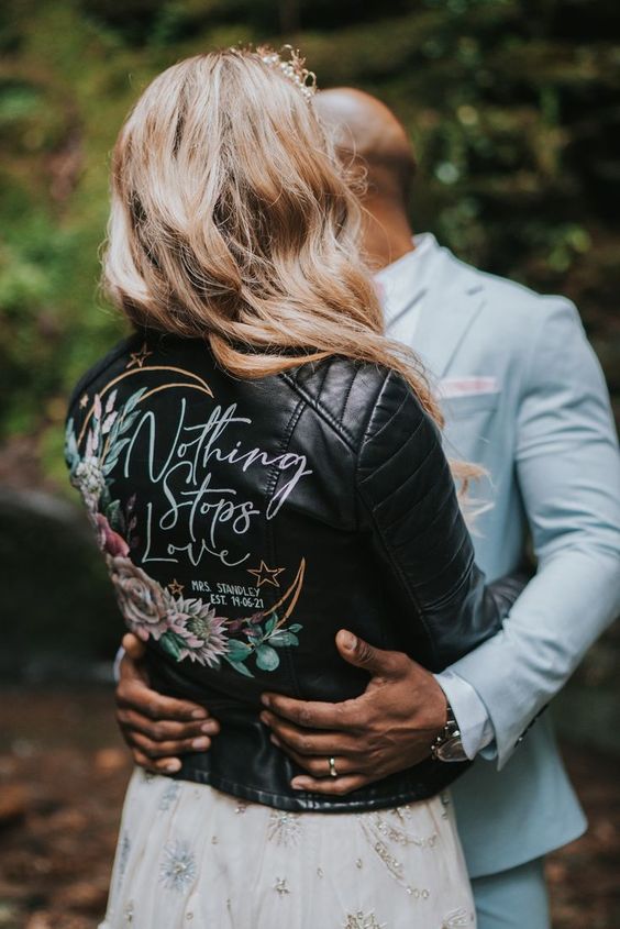 a black leather jacket with a painted half moon, bright blooms and calligraphy is a stylish and catchy idea for a boho bride