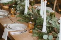 19 an evergreen and greenery table runner dotted with pinecones and with tall and thin candles is a beautiful and cozy idea for a winter wedding