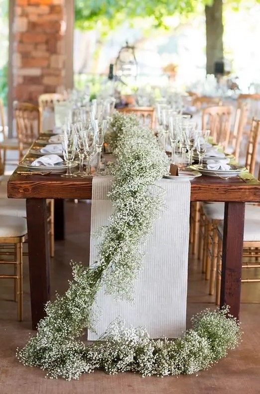 a baby's breath table runner over a neutral fabric one is a great option for a rustic wedding