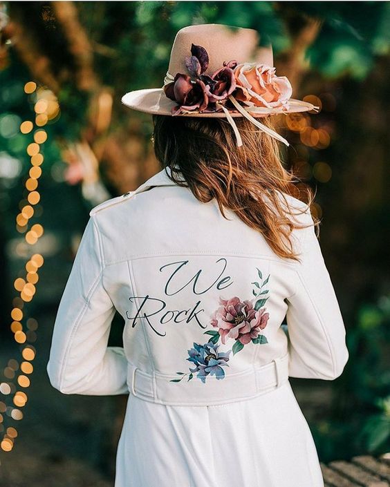 a white cropped leather jacket with bright painted blooms and calligraphy is a stylish and romantic solution for a boho bride