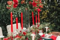 25 a bold Christmassy wedding tablescape with an evergreen and red rose table runner, a tall matching centerpiece, red roses and red napkins