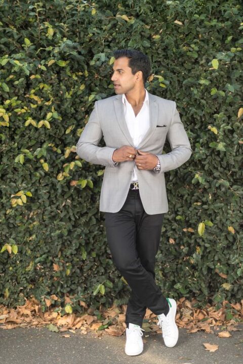 a simple and stylish outfit with a white shirt, a light grey blazer, black trousers, white sneakers will be a fit for a not too formal wedding