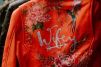 28 an orange cropped leather bridal jacket with bold painted blooms, a humming bird and calligraphy is a super bold and catchy idea