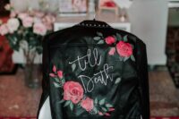 29 a black leather jacket with painted bright blooms and greenery, white calligraphy and studs plus studded shoes for an edgy bride