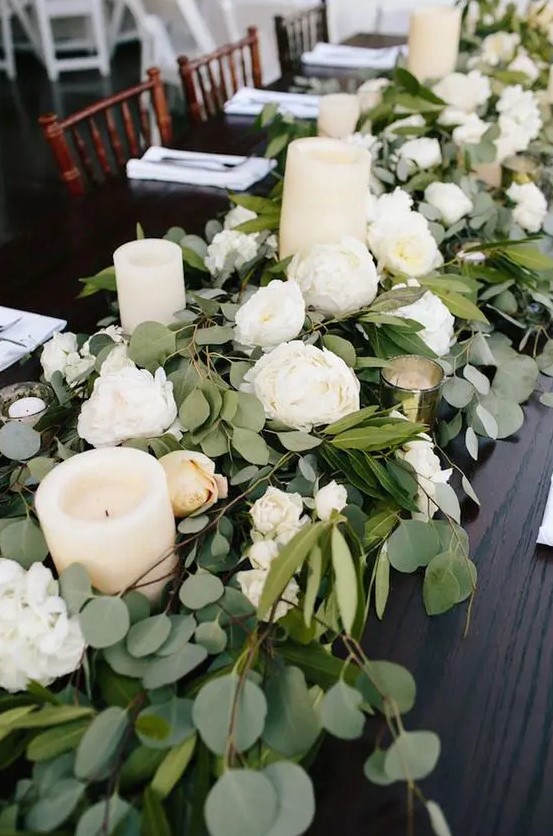 a eucalyptus table runner, white blooms and pillar candles for a timeless and elegant feel
