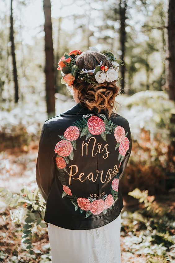 a black leather jacket with painted pink blooms and greenery, with gold calligraphy and a matching floral crown for a woodland bride