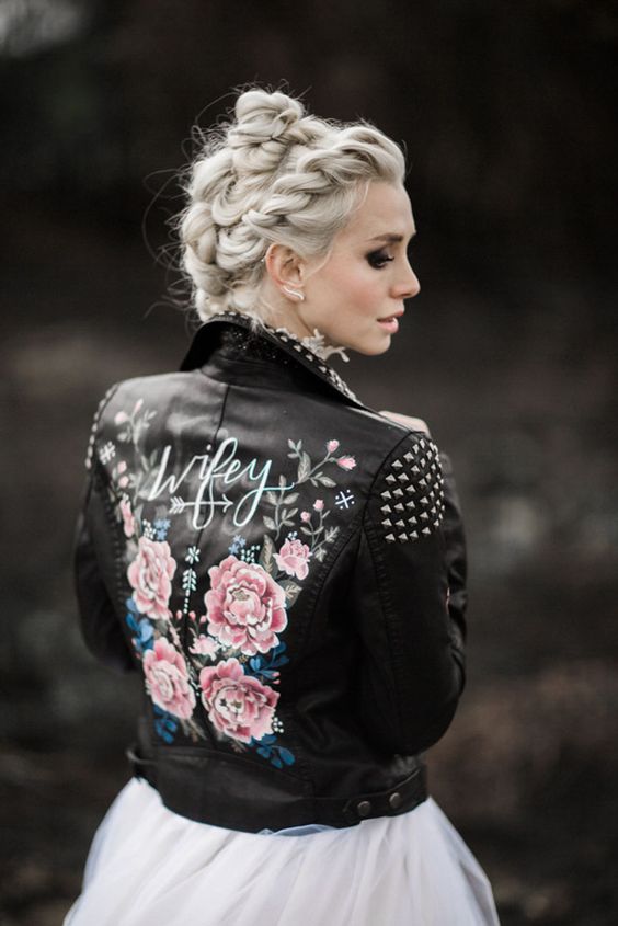 a black leather jacket with studded shoulders and a collar, with a floral paint back and calligraphy is a stylish idea for a bold look