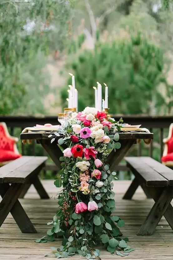 a lush greenery and pink and red flower table runner with candles for a refined tablescape