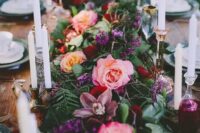 37 a moody floral table runner with blooms of different colors – [ink, mauve, purple and textural greenery dotted with candles