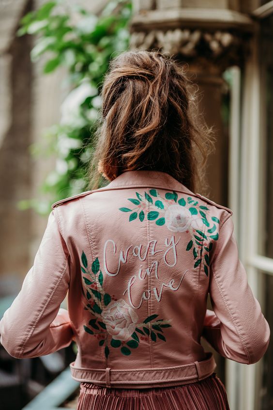 a pink leather jacket with painted  blooms and leaves, with white calligraphy is a stylish idea for a modern bride