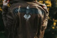 45 a brown leather jacket with fringe and a painted eagle is a great idea for a boho or western bride