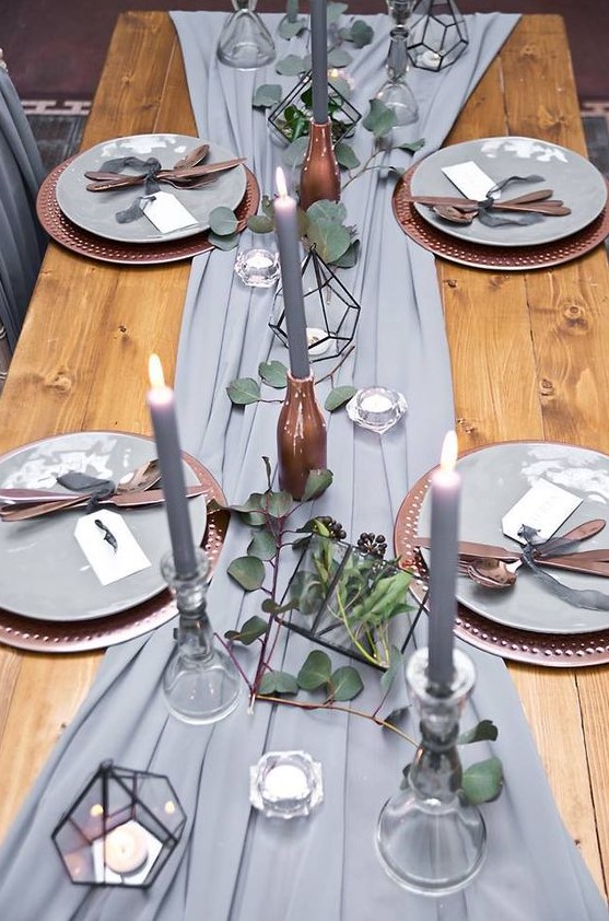 a grey fabric table runner, grey candles, tealights in terrariums and eucalyptus for a refined tablescape