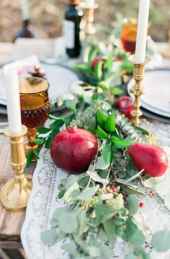 a lush and bold wedding table runner of greenery, pears and pomegranates, berries and thin and tall candles is amazing for the fall