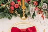 54 a luxurious Christmas wedding tablescape with an evergreen runner, sugared apples, berries and cinnamon sticks, gold rim plates and red napkins
