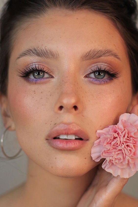 a beautiful bridal makeup with lilac smokeys and lash extensions, a peachy blush and a glossy nude lip, brushed eyebrows