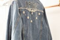 a blue denim bridal jacket with letters and pearls flowers and crystals on the back is a beautiful and not overdone piece to wear
