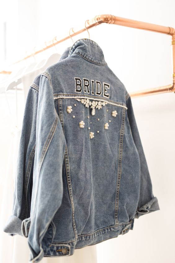 a blue denim bridal jacket with letters and pearls flowers and crystals on the back is a beautiful and not overdone piece to wear