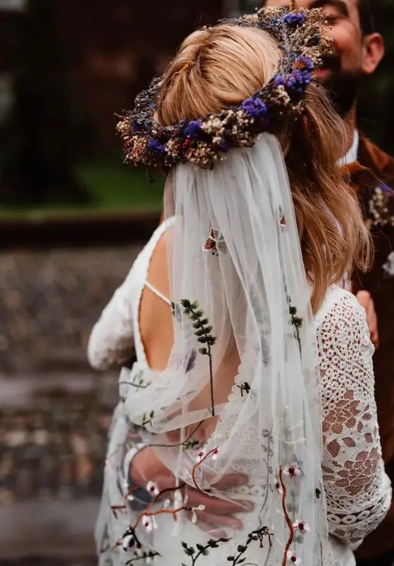 a bold dried and fresh flower crown with purple blooms and herbs and with a floral embroidery veil for a boho bridal look