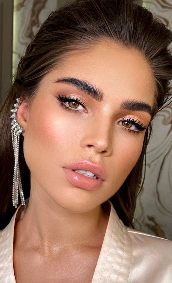 a refined bridal makeup with a glossy nude lip, a touch of blush and beige eyeshadow, lash extensions and brushed eyebrows