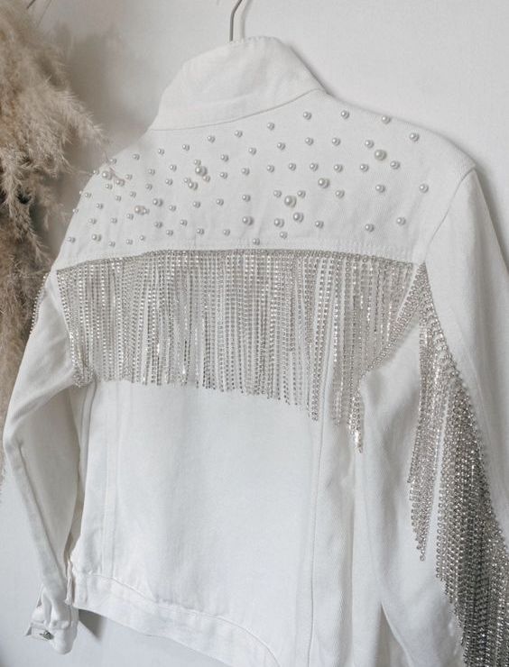 a white denim bridal jacket with pearls on the back and shoulders and long crystal fringe is a chic glam cover up