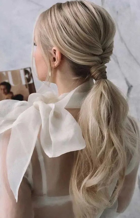 a beautiful and chic low ponytail with a braided touch, a bump on top and some waves down plus locks framing the face